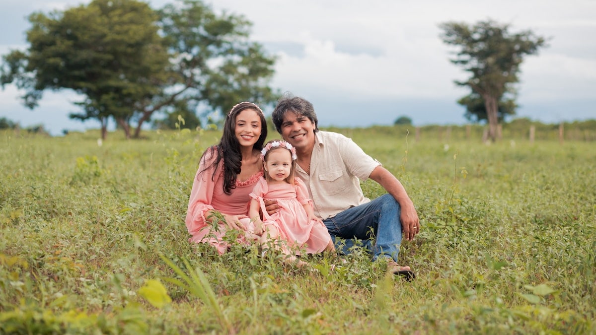 a man, woman and child are sitting in a field